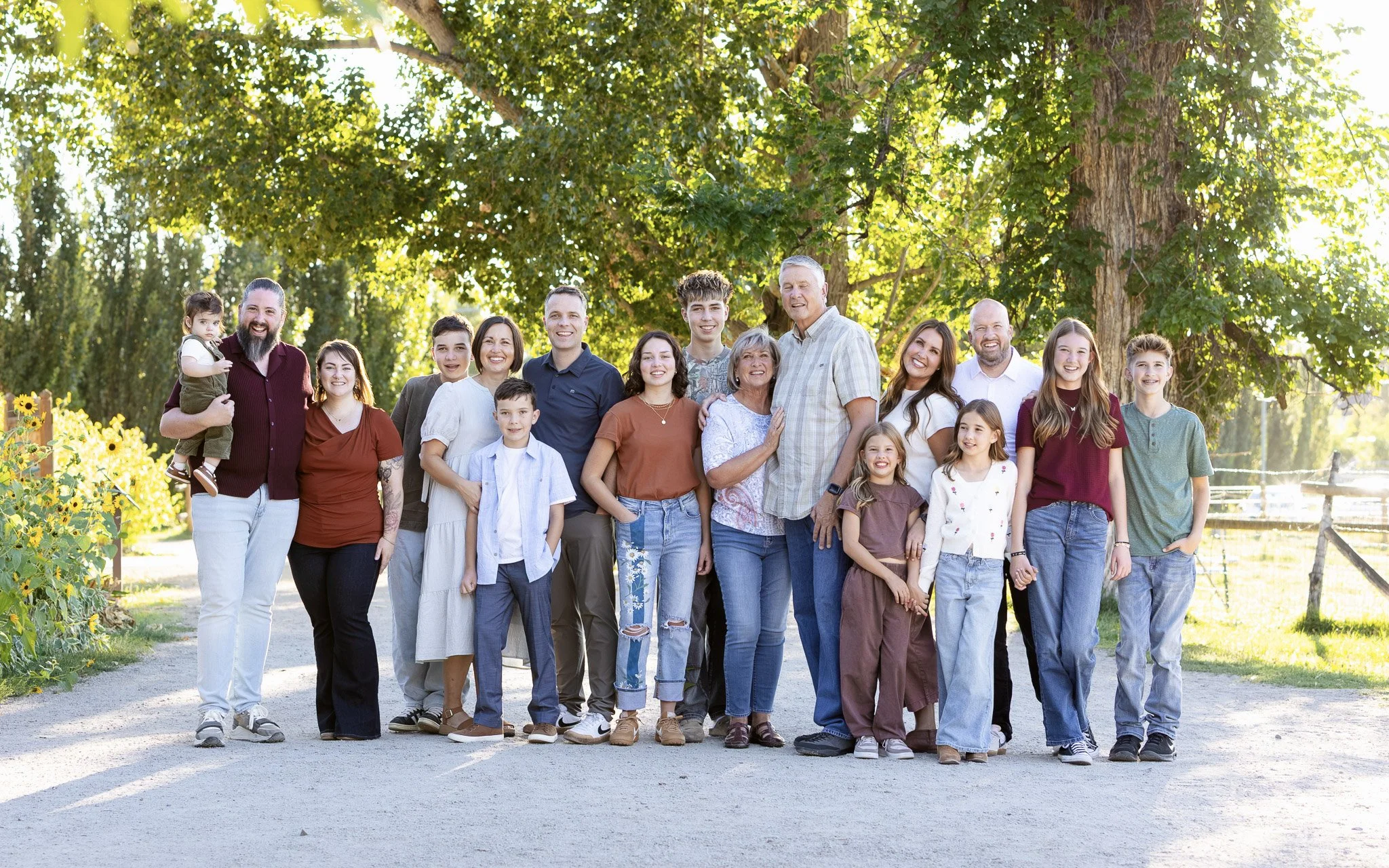 Group photo of wedding family and friends outdoors, with mountains and trees in the background, taken during sunset.