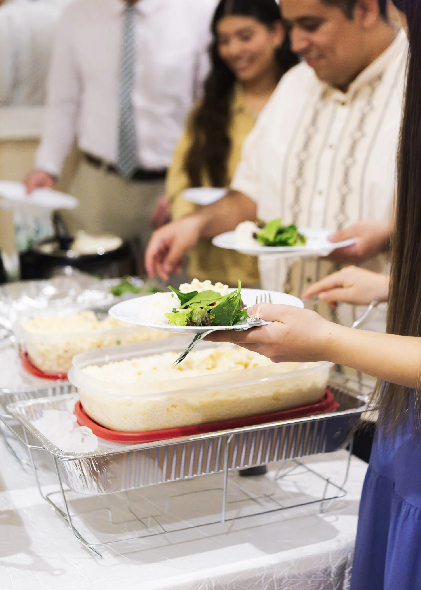 People serving and preparing food at a buffet table.