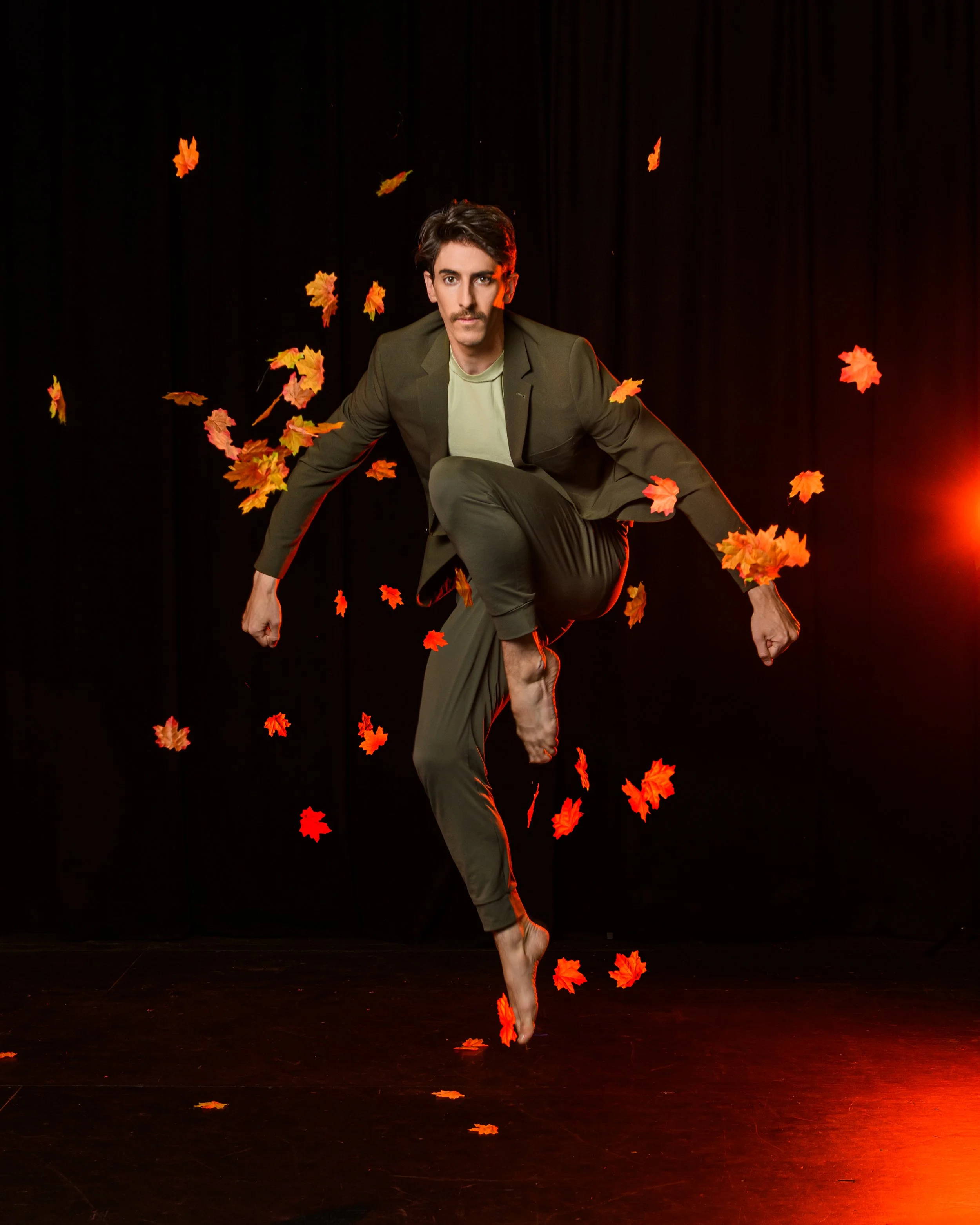 Male dancer leaping through orange autumn leaves in Phluxus2’s touring production of The Red Tree choreographed by Nerida Matthaei