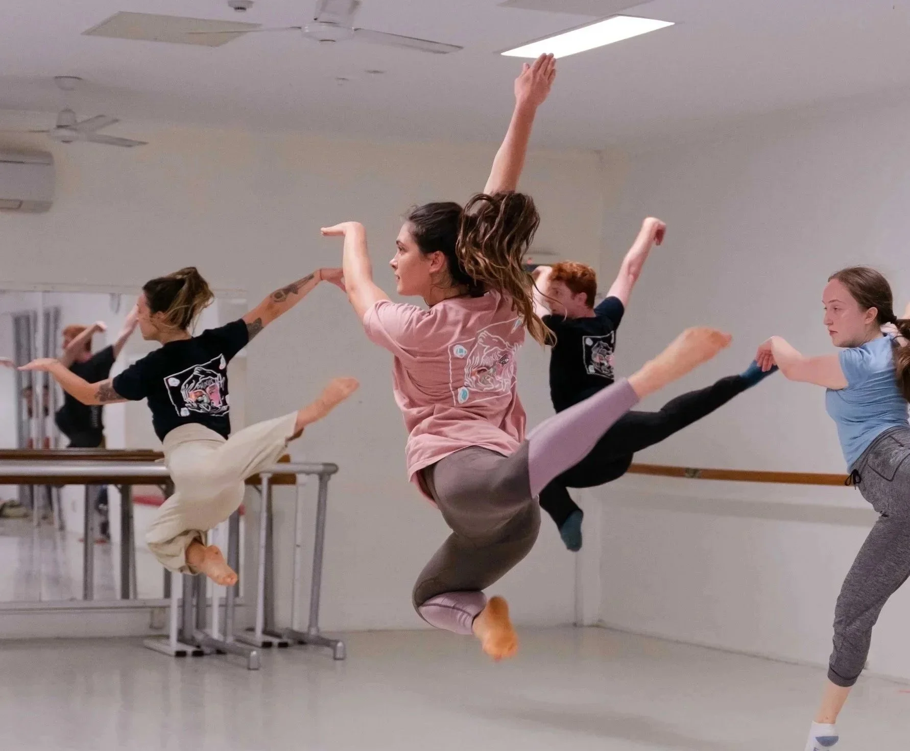 High school and Studio dancers leaping across the studio during a Phluxus2 in-school dance workshop.
