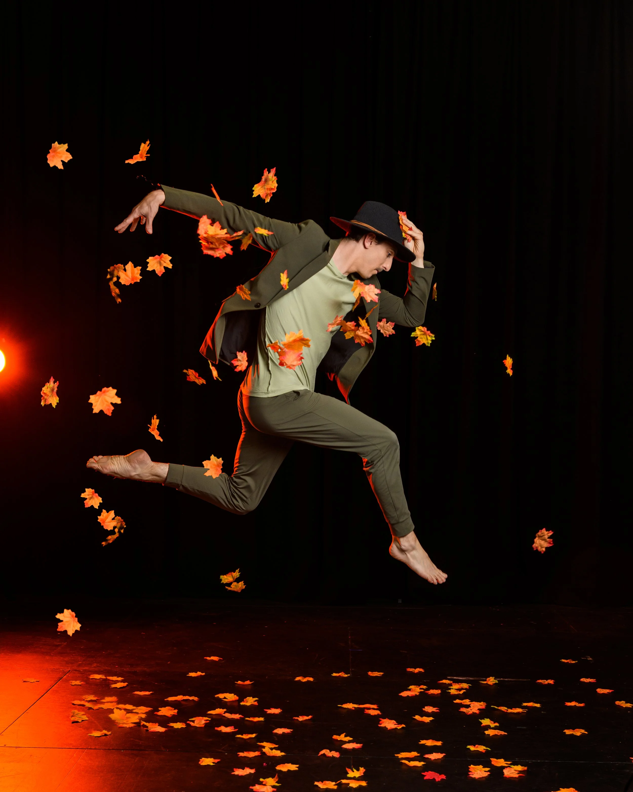 Male dancer leaping through orange autumn leaves in Phluxus2’s touring production of The Red Tree. Directed by Nerida Matthaei
