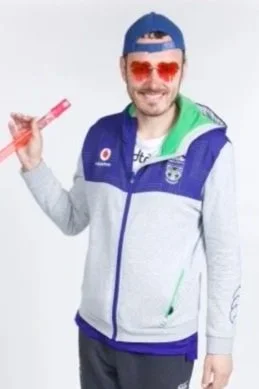Nicholas is wearing red heart sunglasses, a backwards cap, and a sports jacket. He is holding a bubble wand and is smiling.