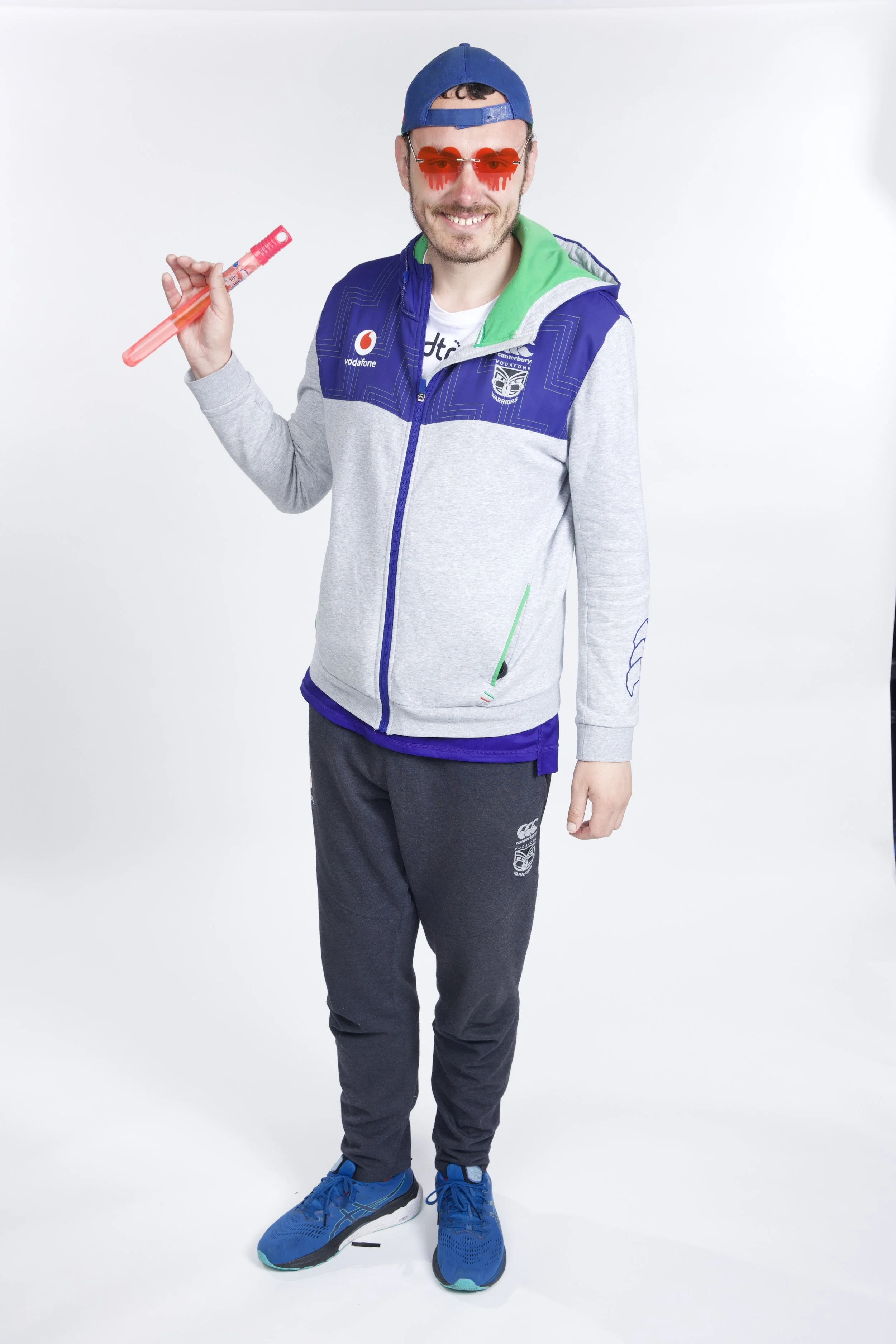 Nicholas is wearing a sports jacket and cap, red heart-shaped sunglasses, and is holding a bubble wand.