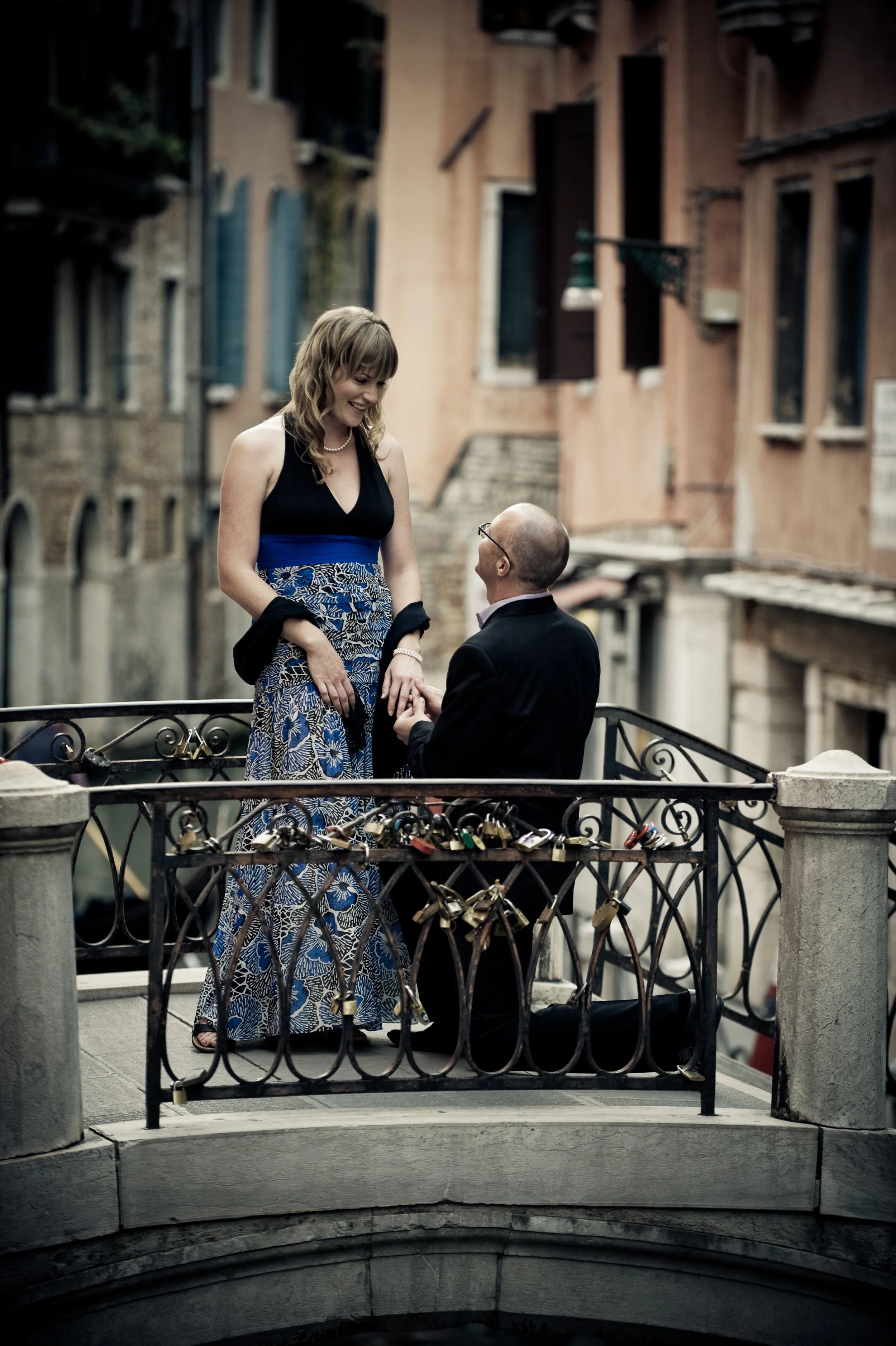 A man on one knee proposal to a woman on a bridge in Venice, Italy.