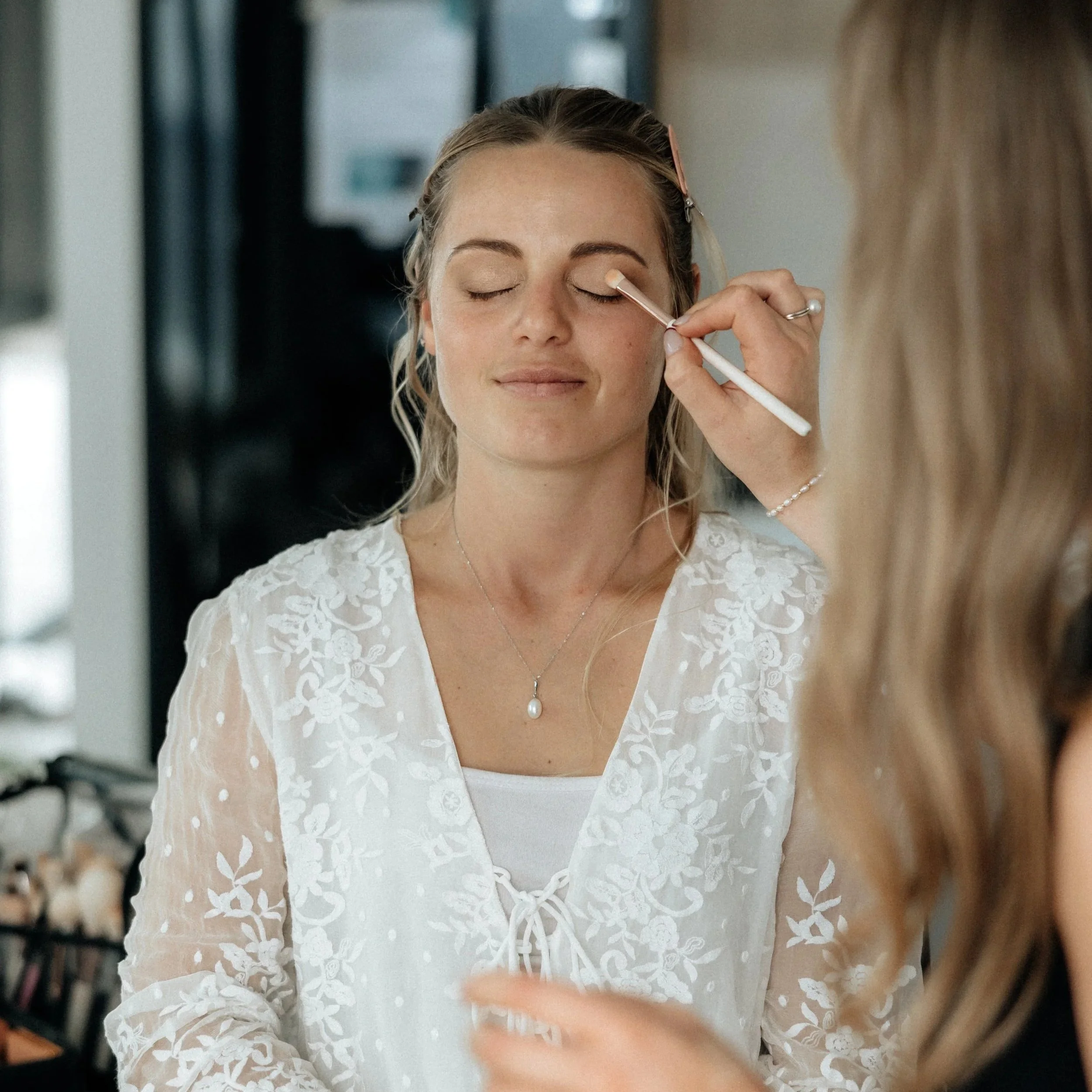 A woman having makeup applied by a makeup artist at a beauty salon.