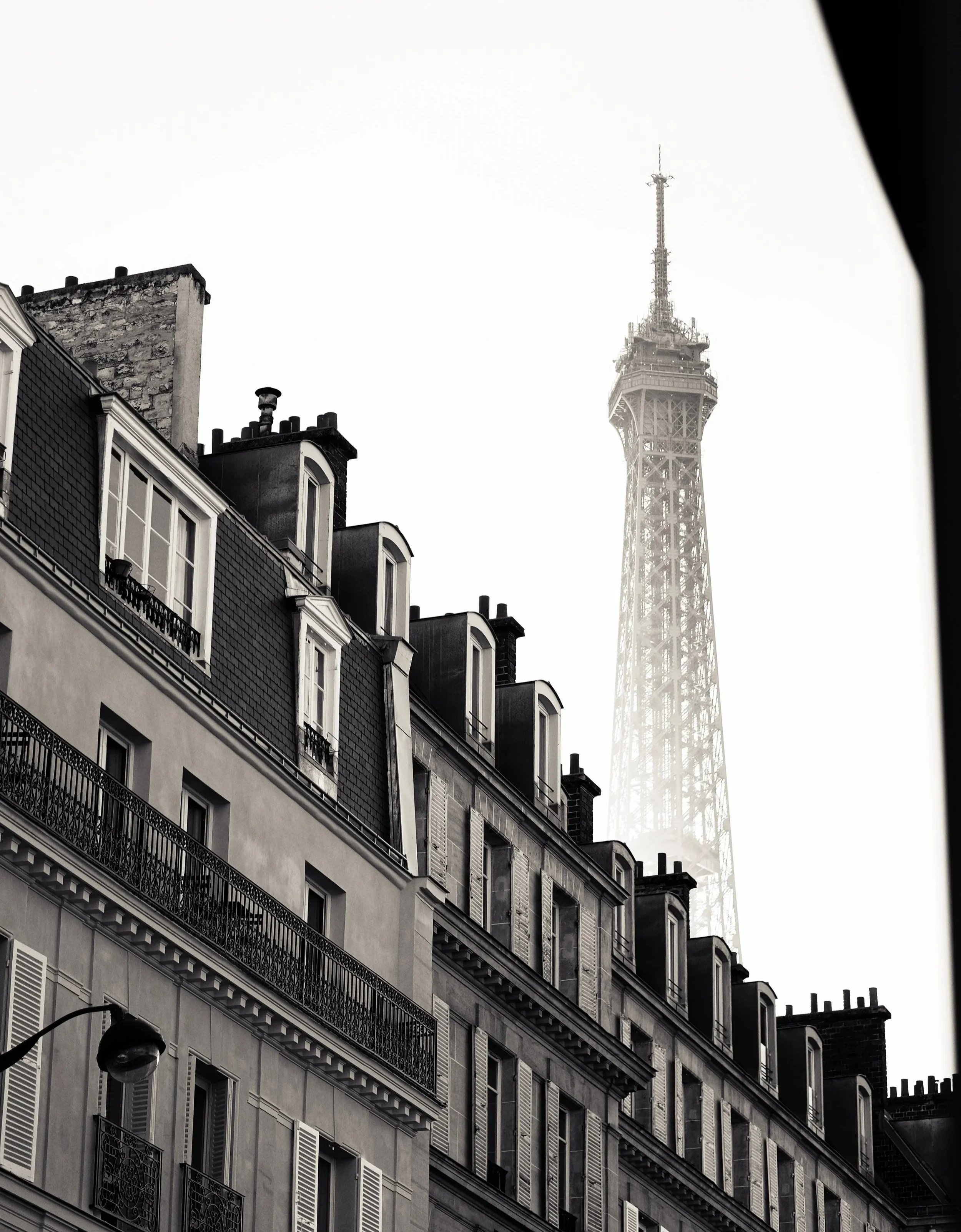 Black and white photo of Paris buildings with the Eiffel Tower visible in the background.