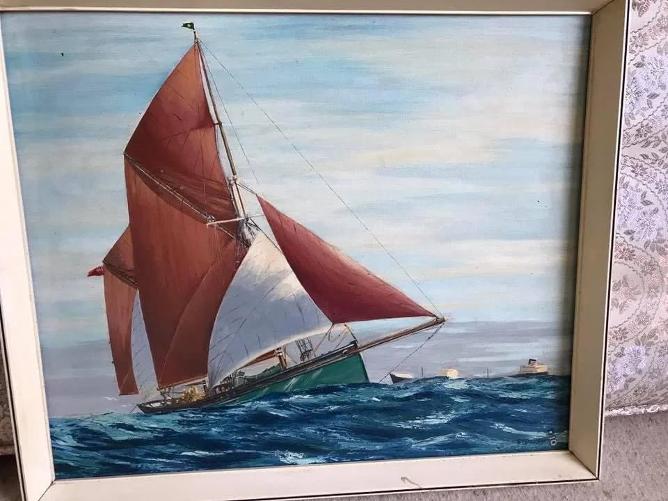 A painting of a sailboat with red and white sails on ocean waves, with a partly cloudy sky in the background.