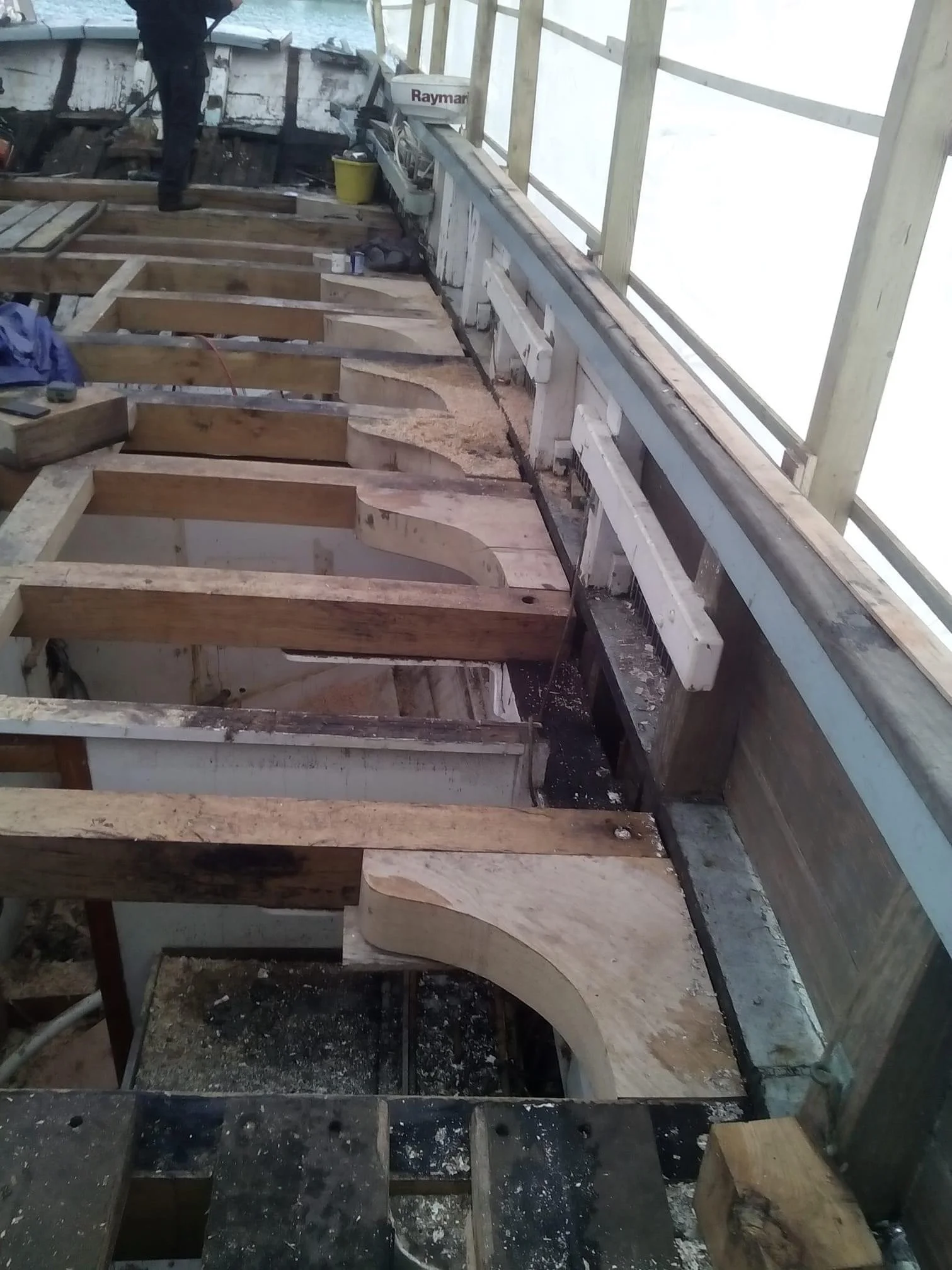Construction site with wooden framework and curved cutouts, overlooking snow-covered landscape.