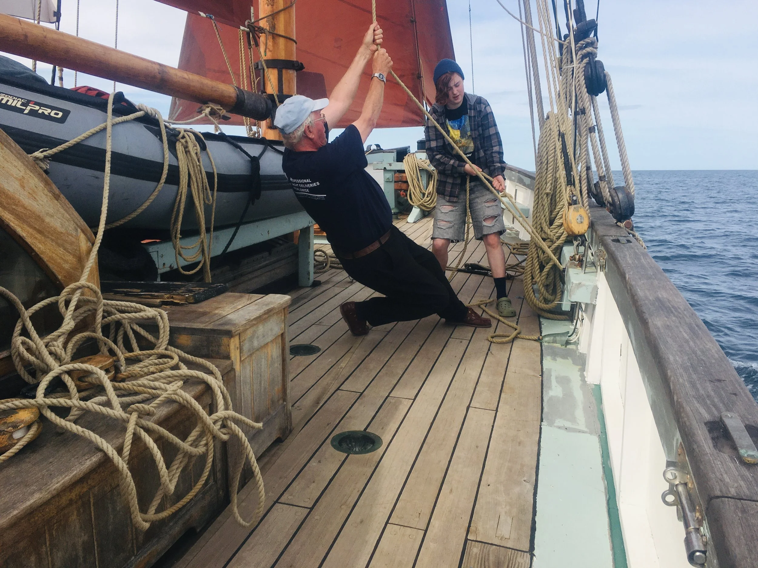 Two individuals on Provident, one pulling a rope while the other helps hold it, with the sea visible in the background.