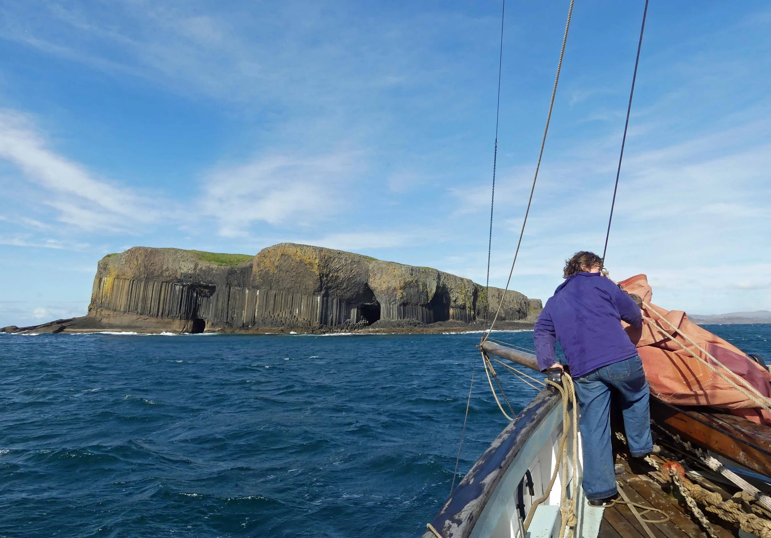 Person on Provident looking at a large island with cliffs, in a blue ocean under a partly cloudy sky.
