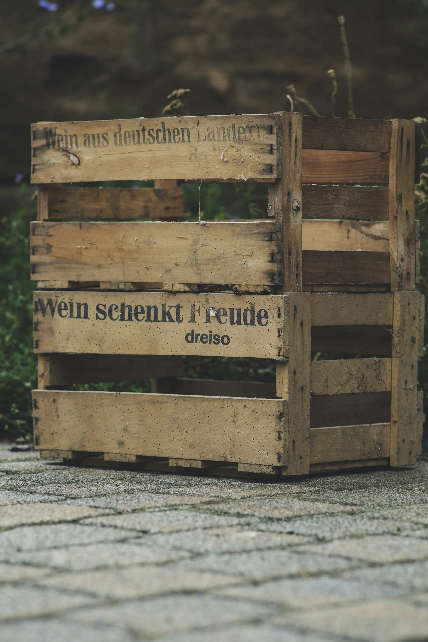 Wooden crates with German phrases on them, placed on a cobblestone surface outside.