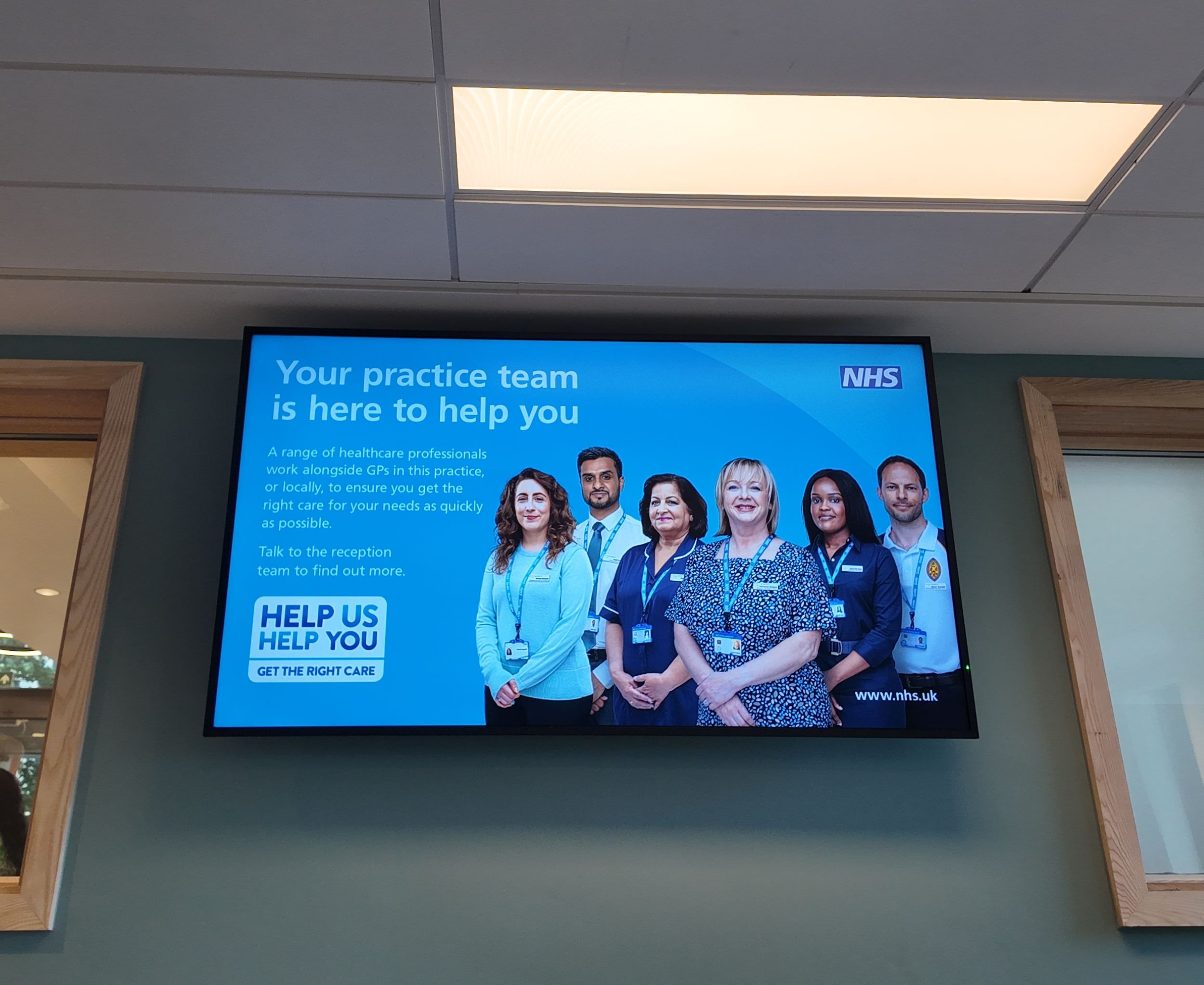 Media display screen in a GP practice showing a NHS poster
