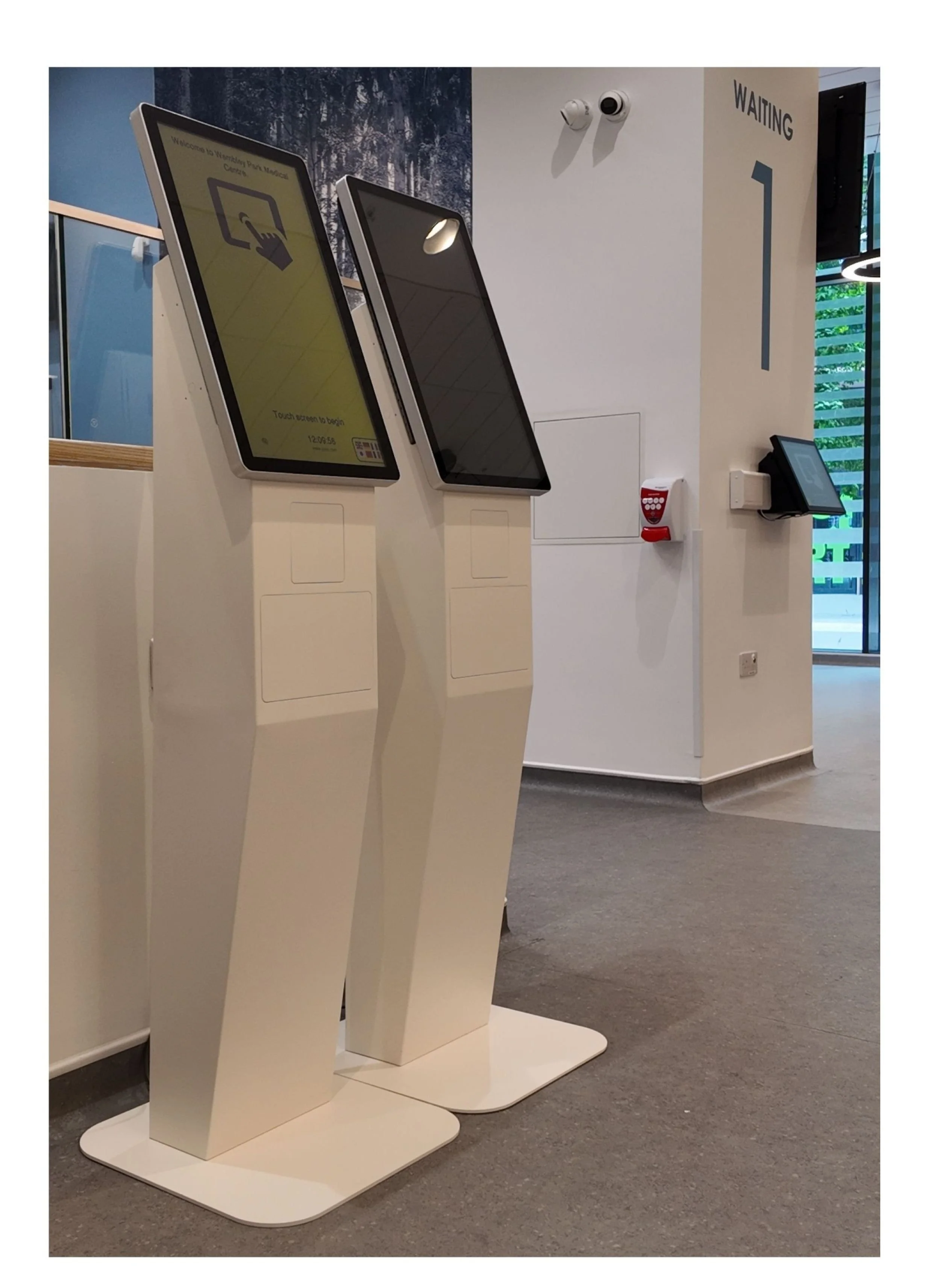 a surgery entrance with two patient check in kiosks and a wall mounted patient check in touchscreen