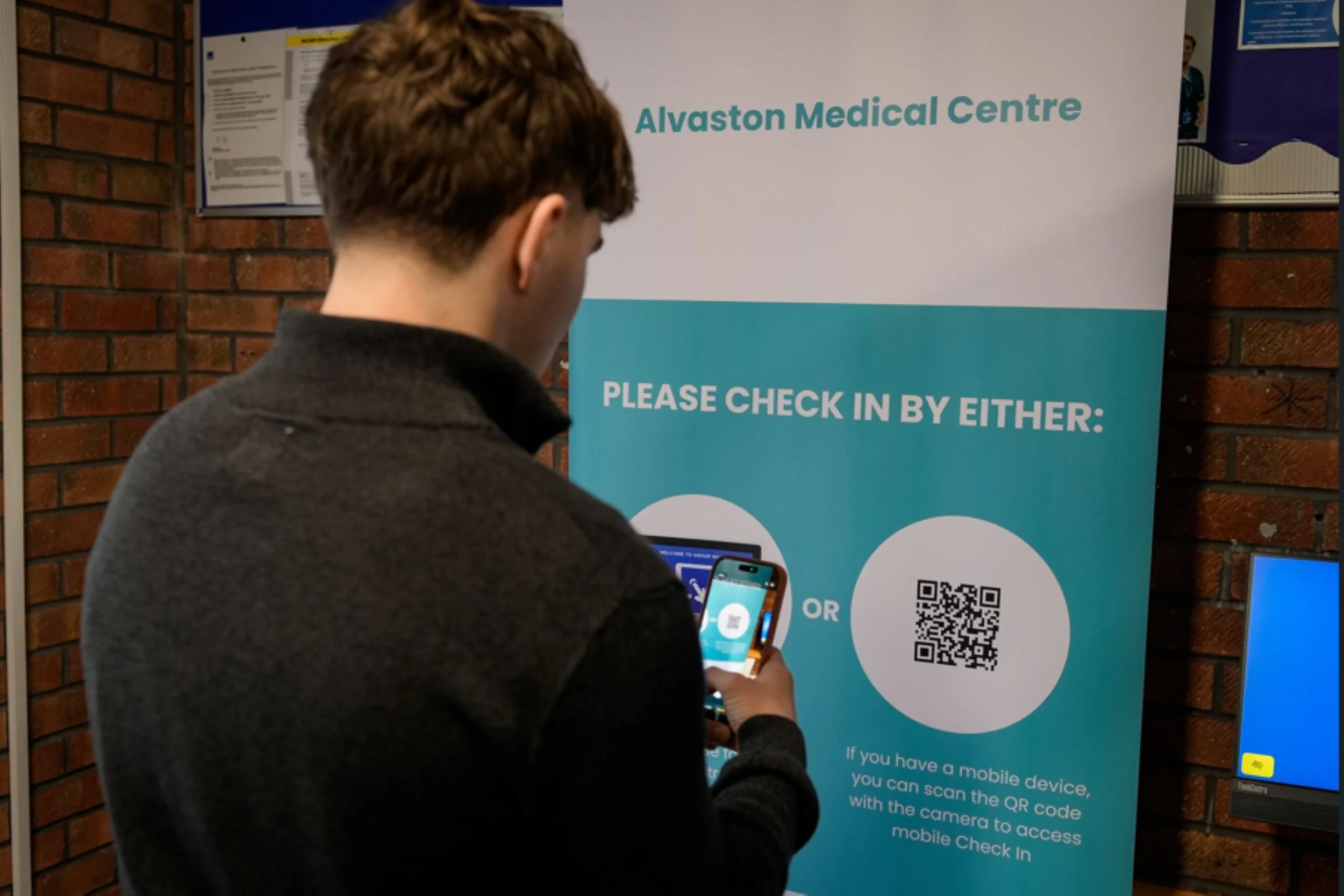 a patient checking in to a GP practice by scanning a QR code to access mobile patient check in system