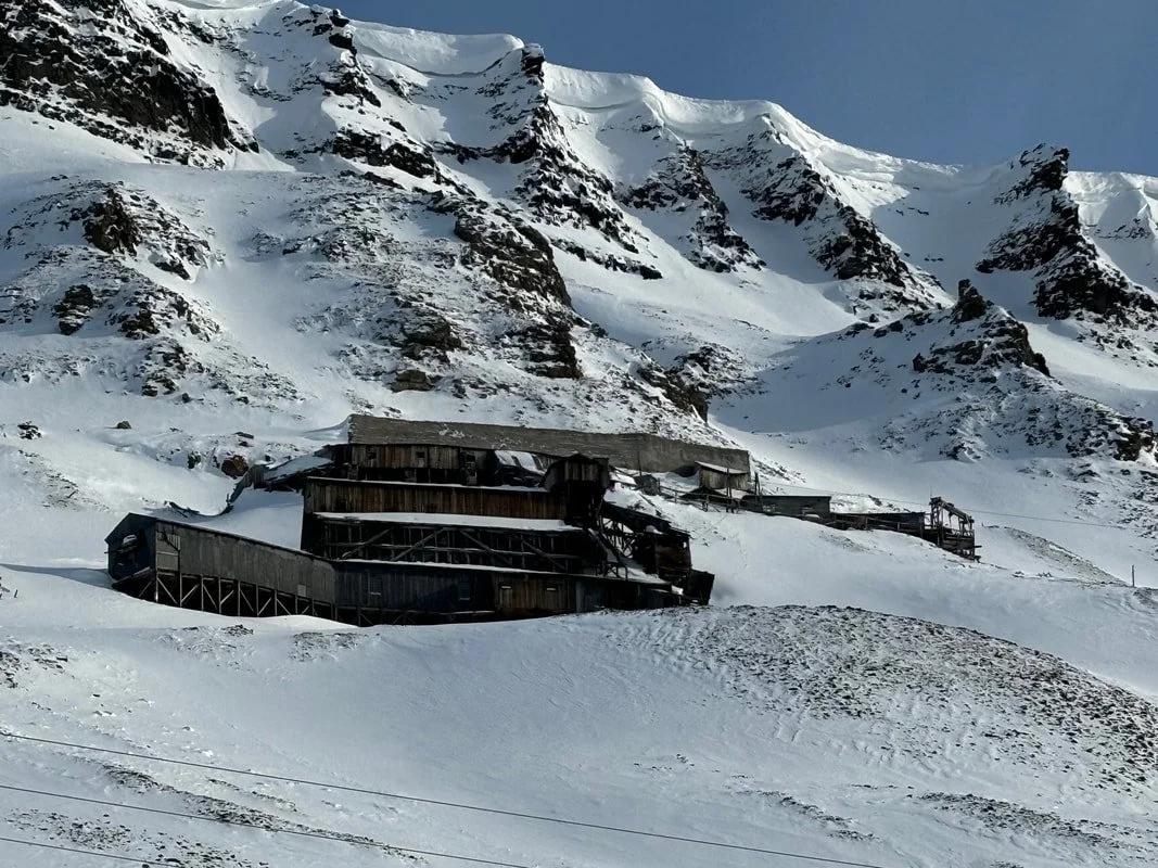 Struttura in legno su una montagna innevata con alte cime e crepacci, Longyearbyen, Isole Svalbard.