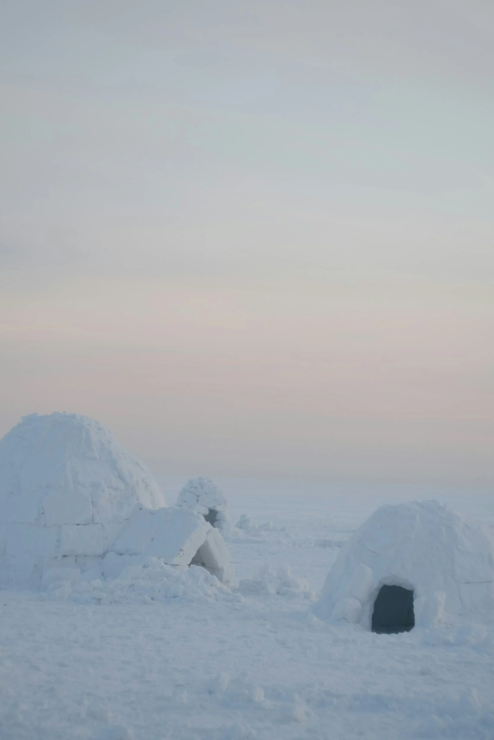 Tra i igloo di ghiaccio in un paesaggio innevato sotto un cielo pastello.