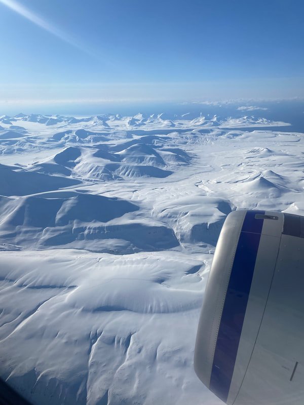 Veduta dall'aereo della vasta distesa di ghiaccio e neve alle Isole Svalbard, con creste e valli di ghiaccio sotto un cielo sereno.