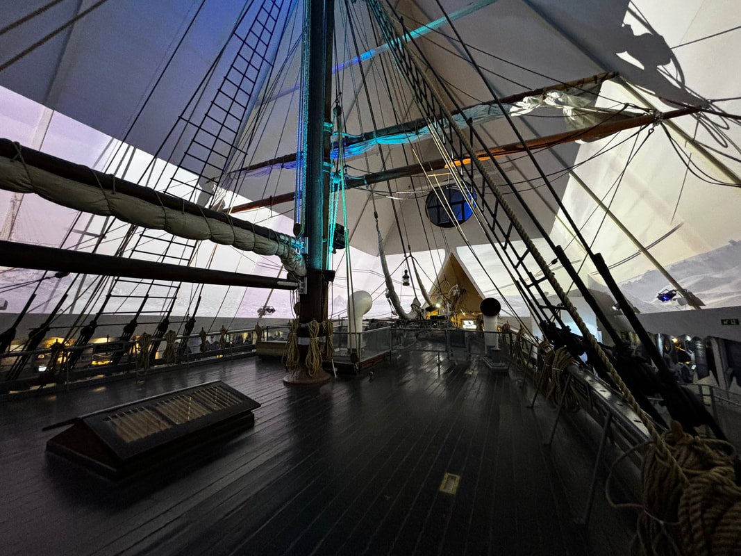 Interno della nave Fram con corde, alberi e vele, illuminata con luci blu e bianche.