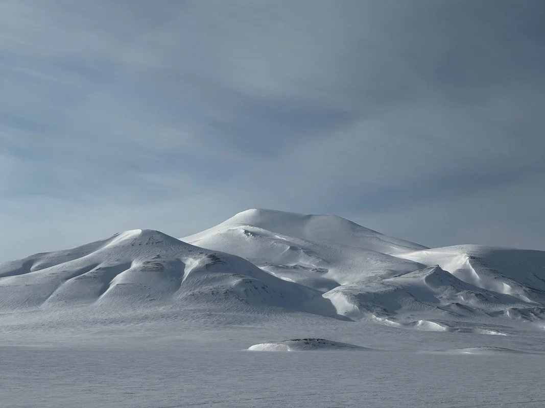 Paesaggio ghiacciato con collinette di neve e cielo nuvoloso, Tempelfjörd, Isole Svalbard.