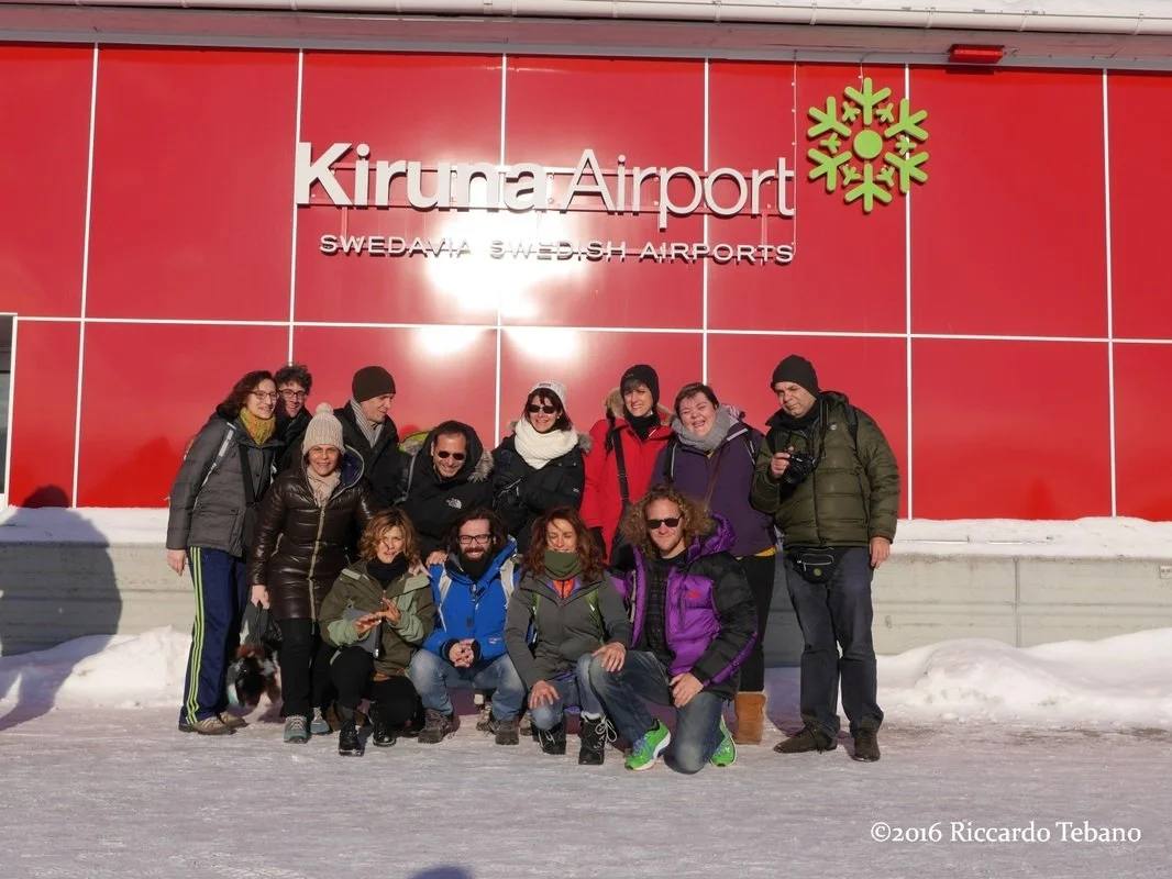 Gruppo di persone sorridenti di fronte all'ingresso dell'aeroporto di Kiruna in Svezia.