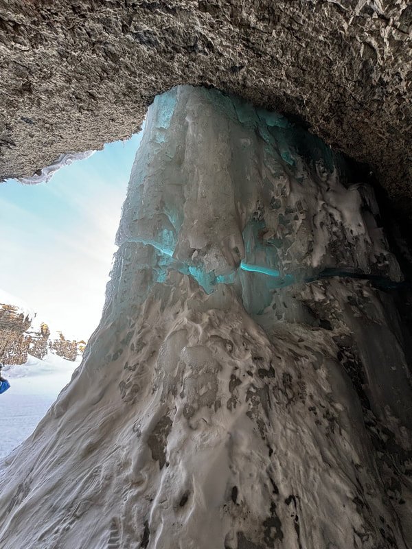 scogliera di ghiaccio con crepe blu, vista da una grotta in inverno