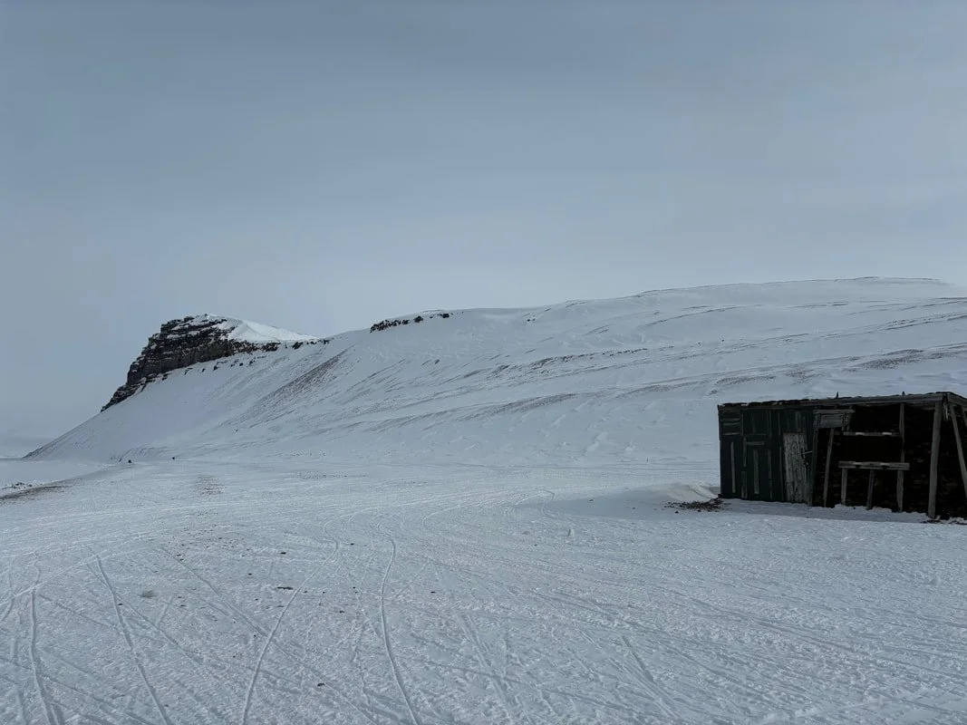 Paesaggio invernale con montagna innevata, cielo nuvoloso e vecchio capanno di legno, Tempelfjörd, Isole Svalbard.