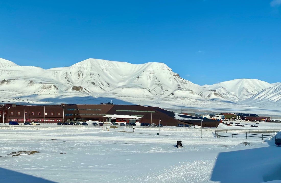 Paesaggio invernale con edifici e montagne innevate sotto un cielo blu, Longyearbyen, Isole Svalbard.