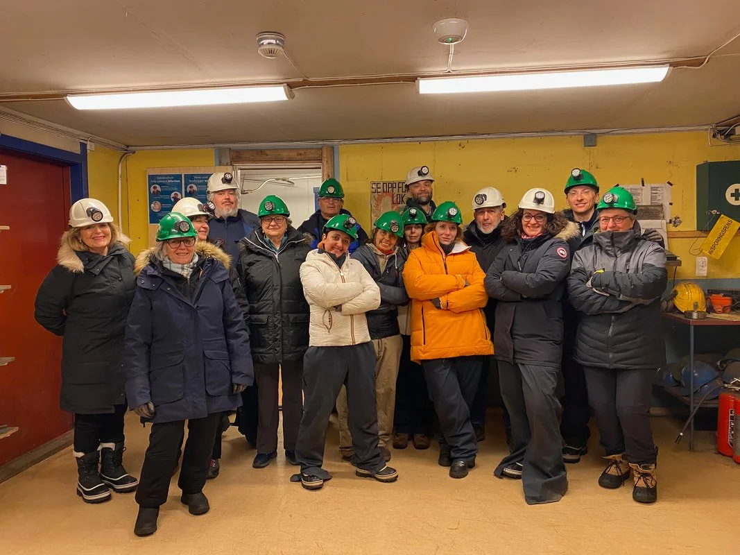 Gruppo di persone in abbigliamento da lavoro e caschi in un ambiente industriale o di cantiere in una miniera a Longyearbyen alle Isole Svalbard.