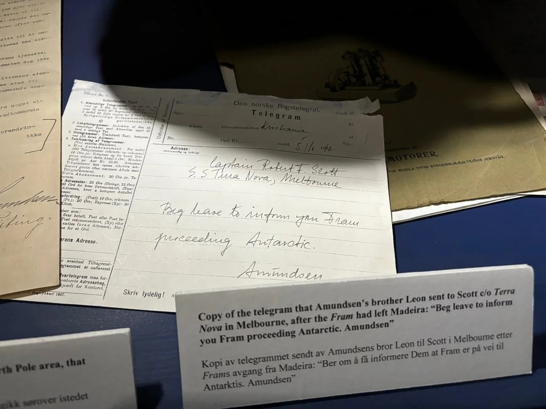 Appunti e telegramma su una scrivania, con vari documenti e note scritte. Il telegramma è in inglese e italiano, e menziona un messaggio inviato da Leon Amundsen a Scott in Melbourne, riguardante un viaggio in Antartide.