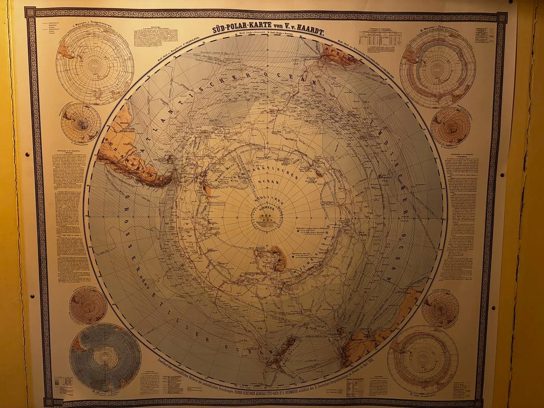 Carta geografica dell'emisfero meridionale con dettagli di latitudini, longitudini e mappe delle regioni antartiche in toni marrone e beige.