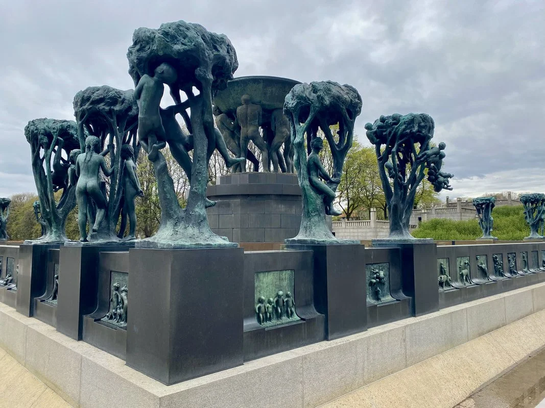 Statue del parco Vigeland a Oslo con sculture di figure umane e alberi stilizzati, disposta su un basamento di pietra, all'aperto sotto un cielo nuvoloso.