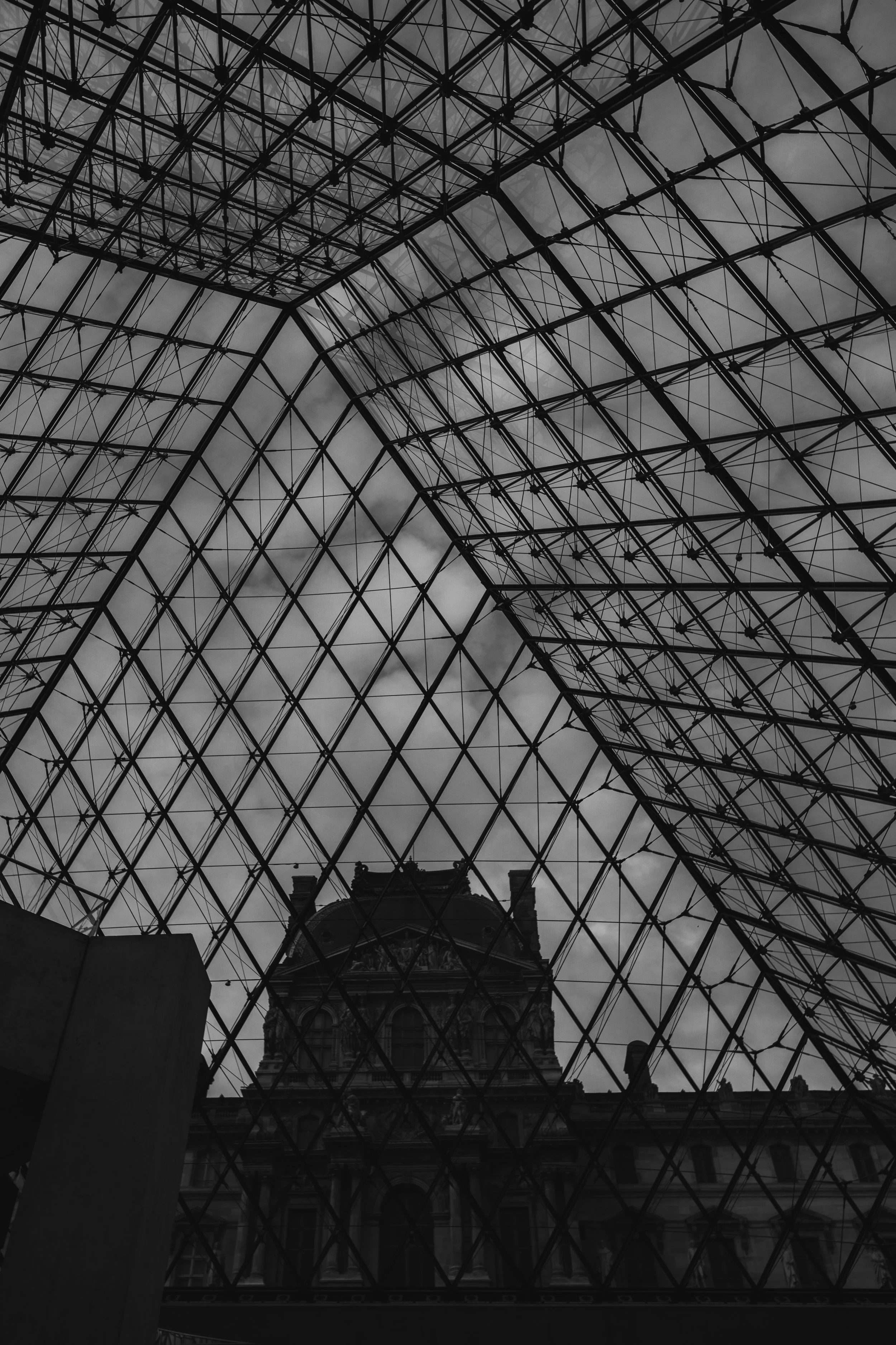 Interior view of a glass and metal dome ceiling with a historic building visible through the structure.