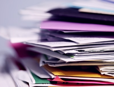 A stack of disorganized papers and folders in various colors and sizes.