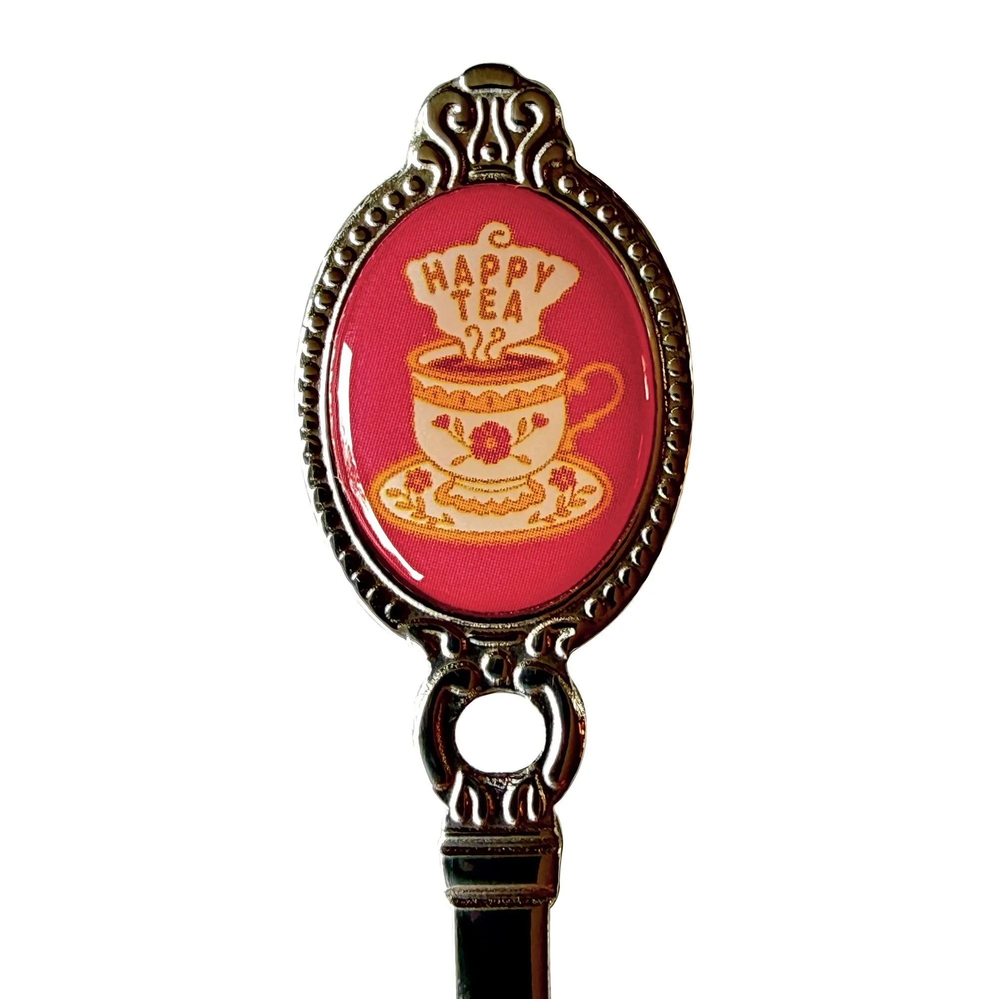 Close-up of the hot pink Happy Tea teaspoon crest, a teacup with a smiling face