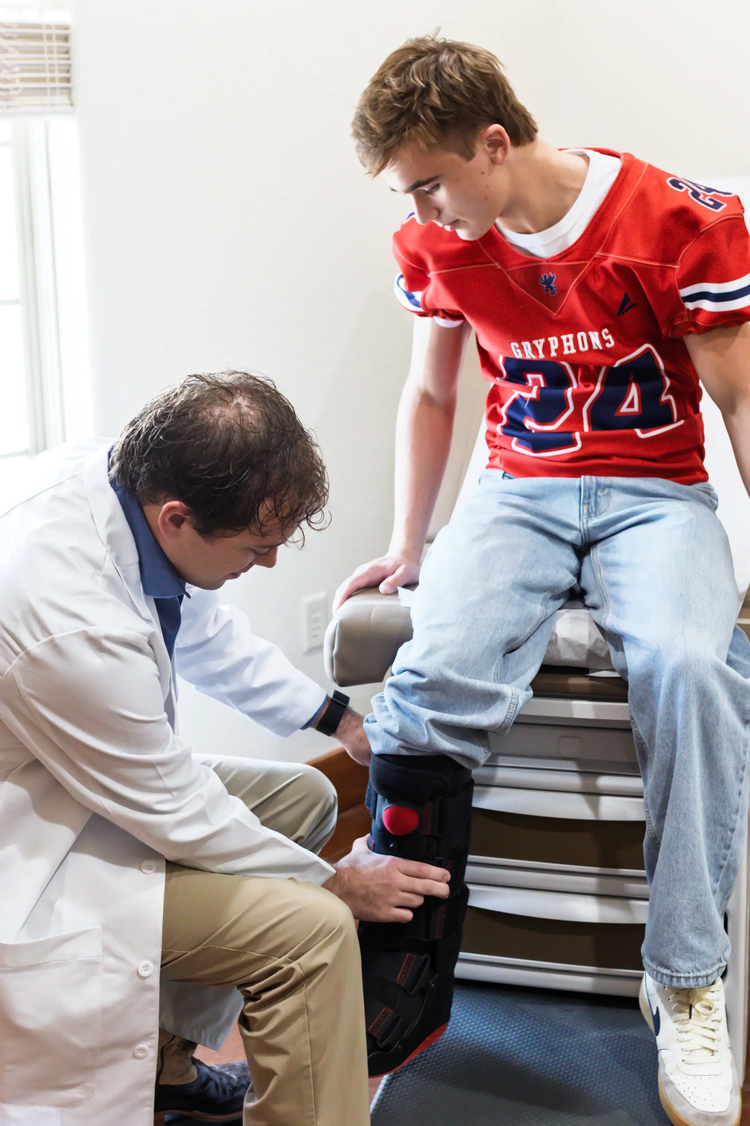 Physician at The Clinic at Glen Rose providing sports medicine care to a teenage athlete with a knee injury.