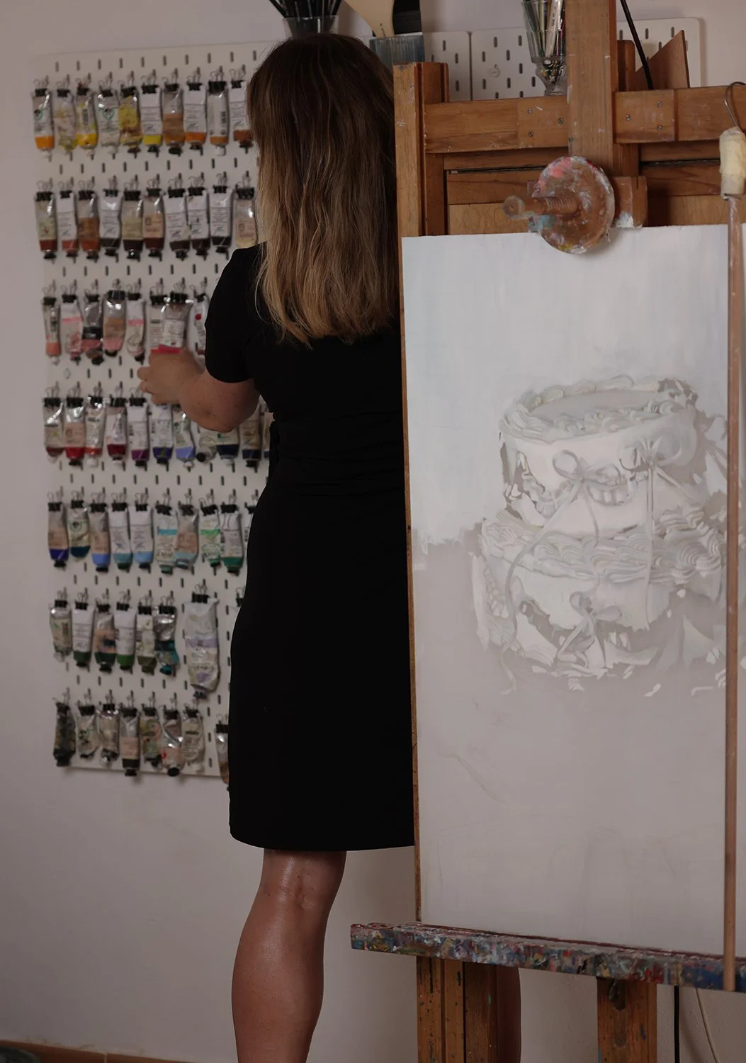 With Compliments, Artist standing next to a painting by Tereza Barnard showing a cake, cake adorned with ribbons, structurally unstable dessert, You Shouldn't Have series