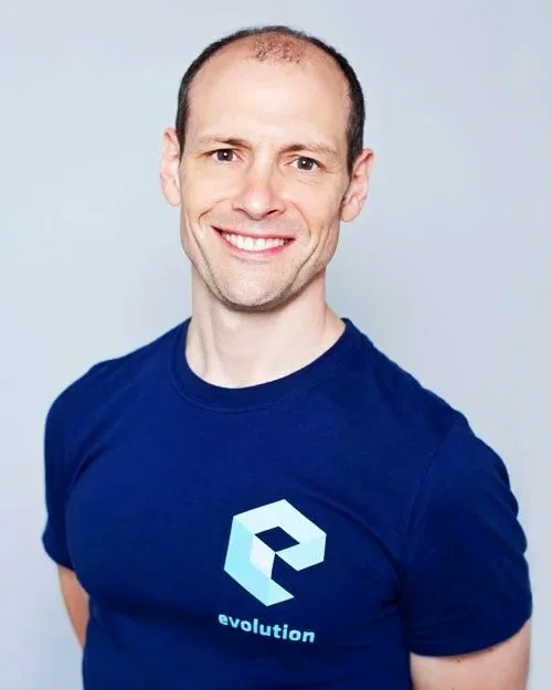 Man with short hair, wearing a blue t-shirt with a logo and the word "evolution" on it, smiling at the camera.