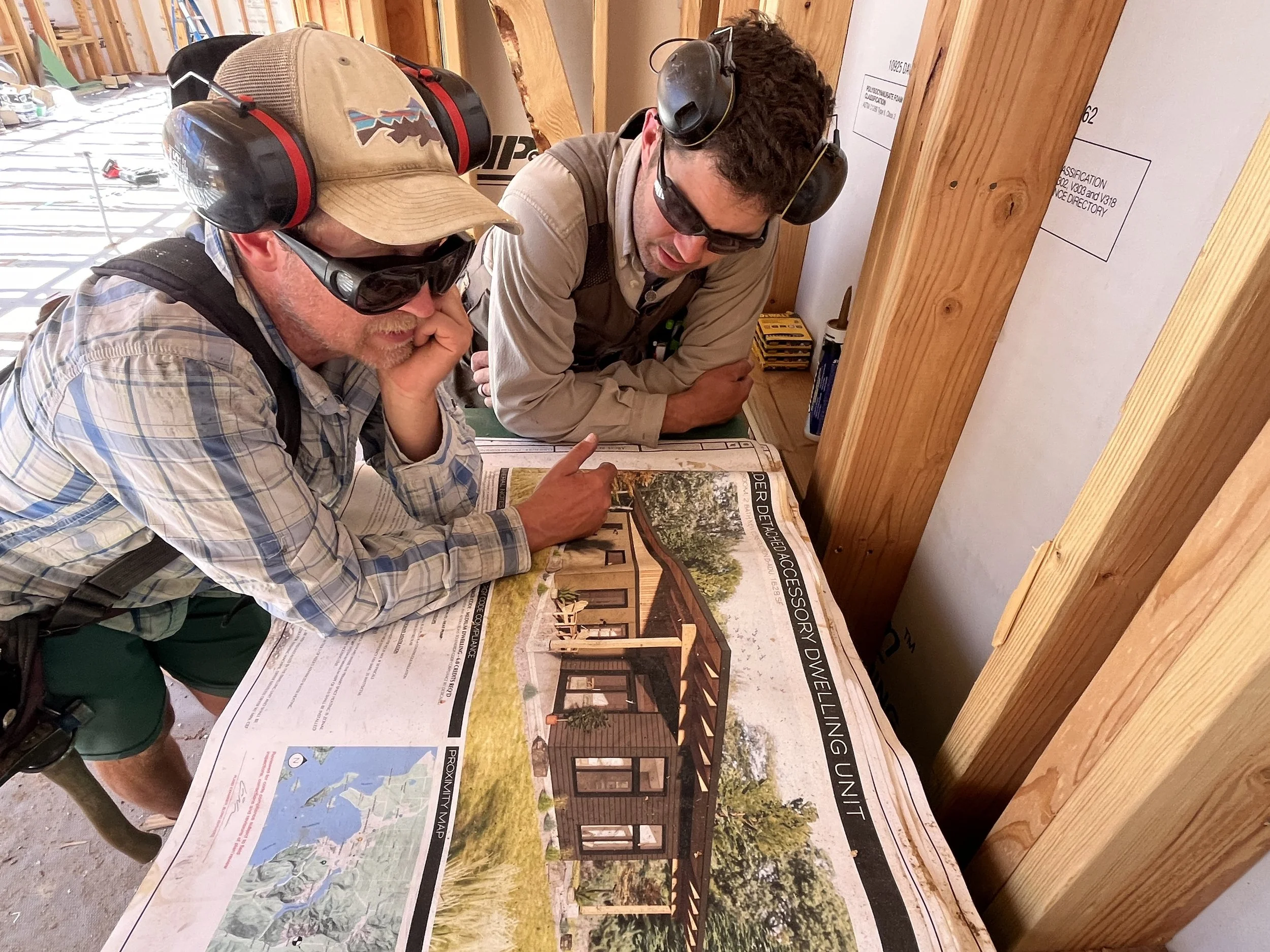 Two construction workers examining a blueprint of a building project at a construction site.