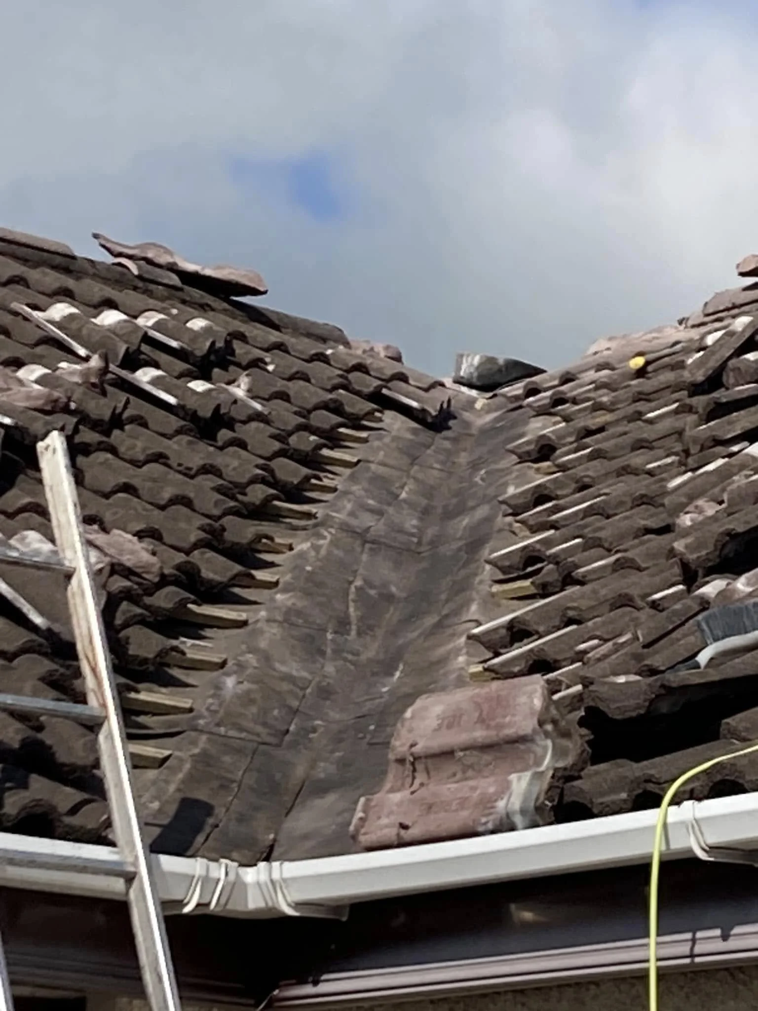 Storm damaged roof with tiles lifted and battens exposed