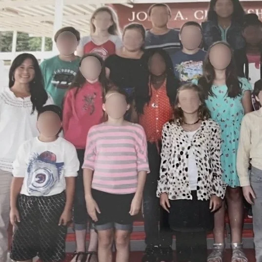 Ms. Lo's former 5th grade class: Group of children and their teacher on steps in front of a school building.