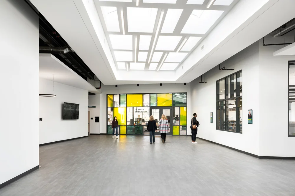 Library lobby under a coffered skylight, with a yellow glass wall beyond
