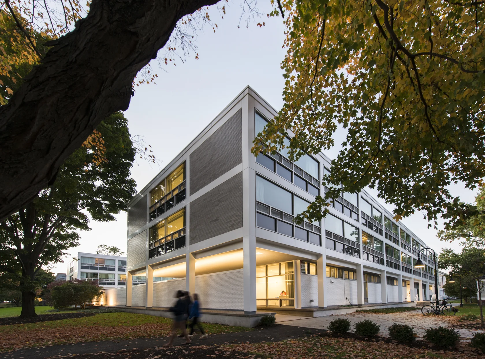 The renovated residence halls at dusk, framed by autumn trees