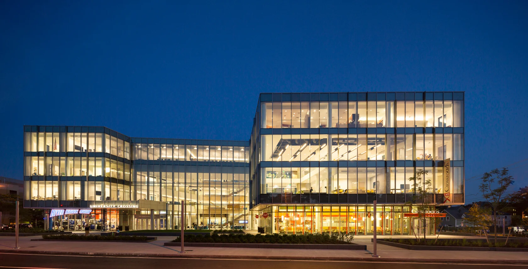 University Crossing at dusk, its glass walls lit, two stacked volumes