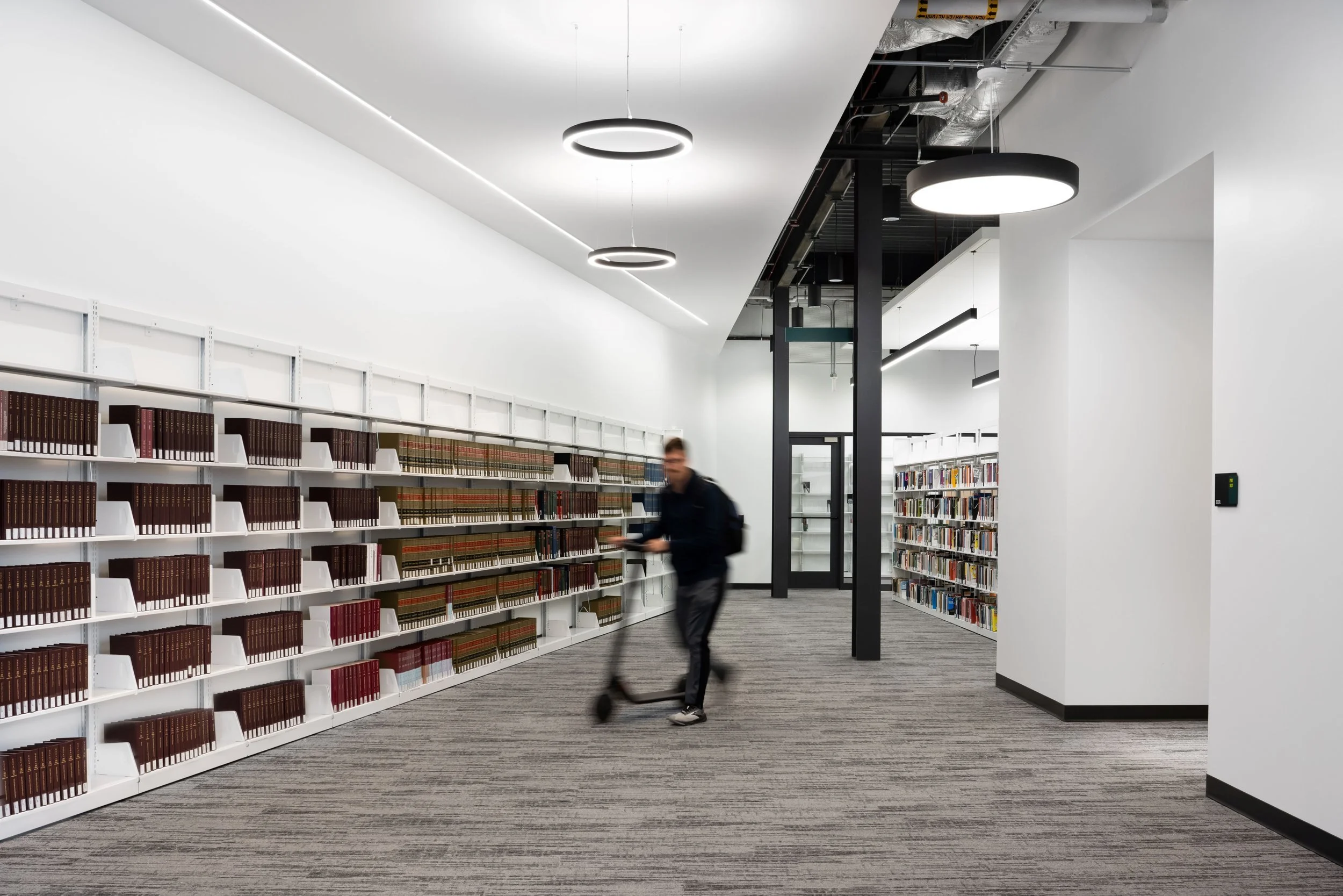 19-zaffere-library-a-student-riding-a-scooter-past-the-stacks.jpg