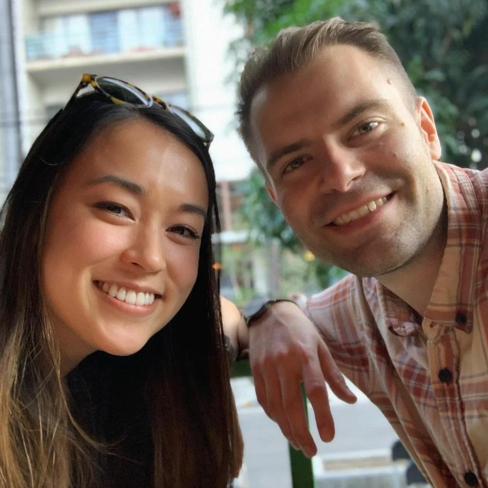 A smiling woman and man taking a selfie together outdoors.