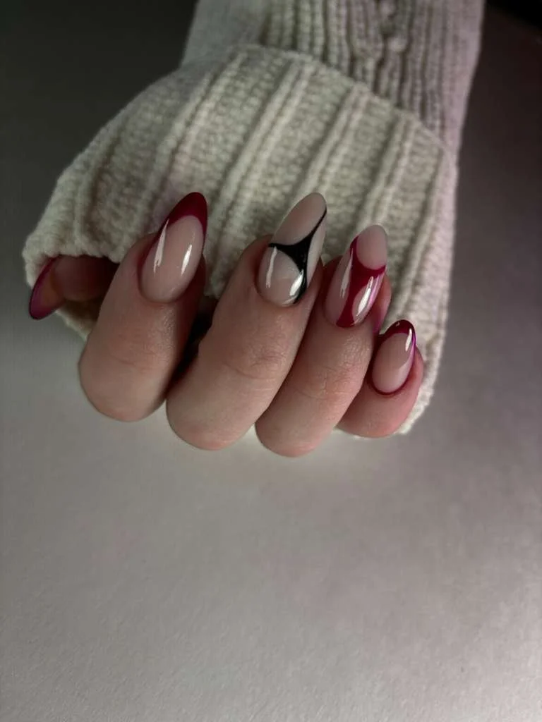 Close-up of a hand with manicured nails, wearing a beige sweater sleeve.