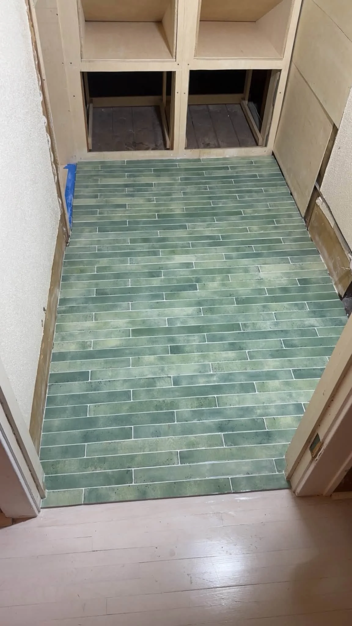 An image of a seafoam green tile floor. The tiles are long and skinny and stacked horizontally.