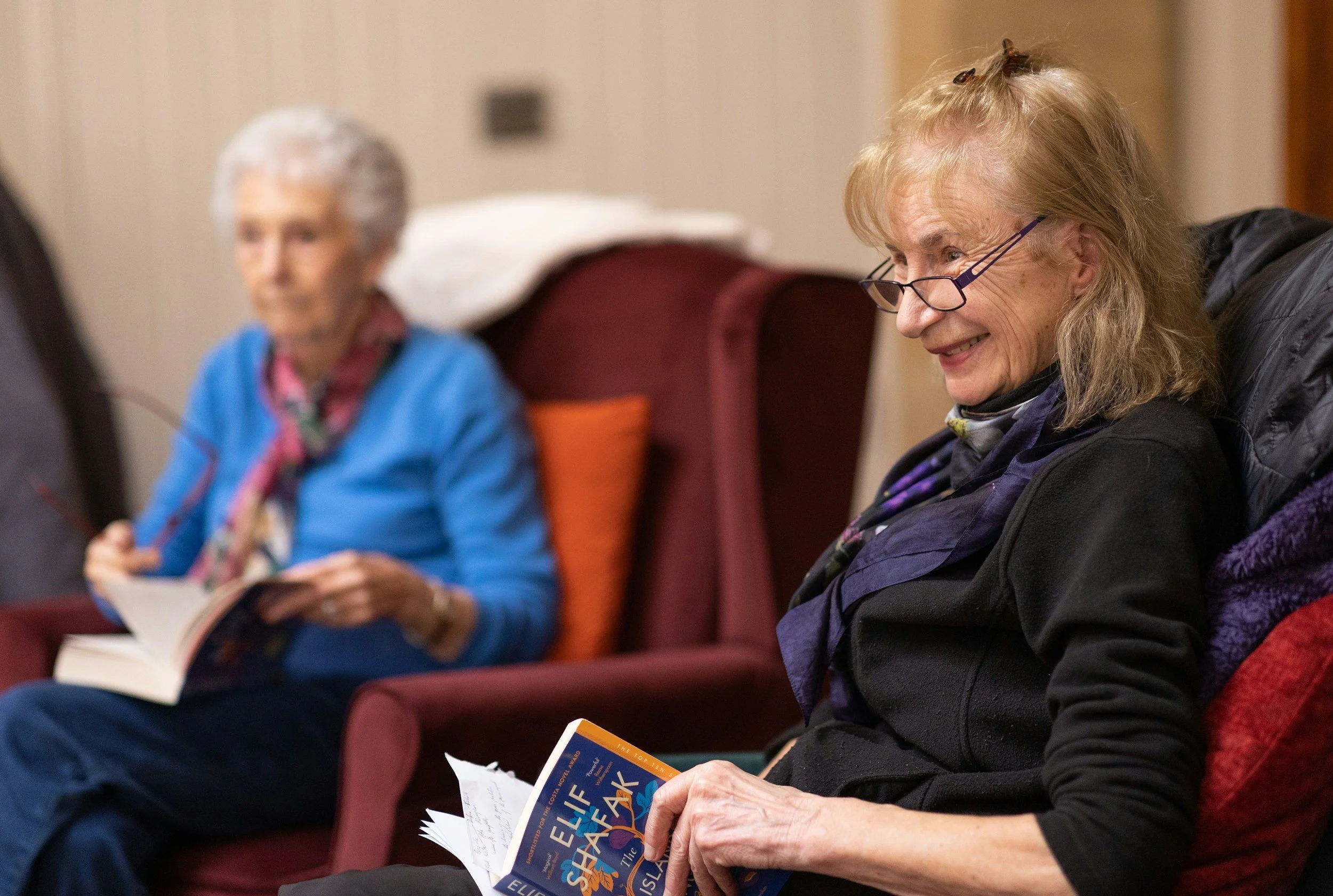 Two women sitting in chairs with open books in their laps
