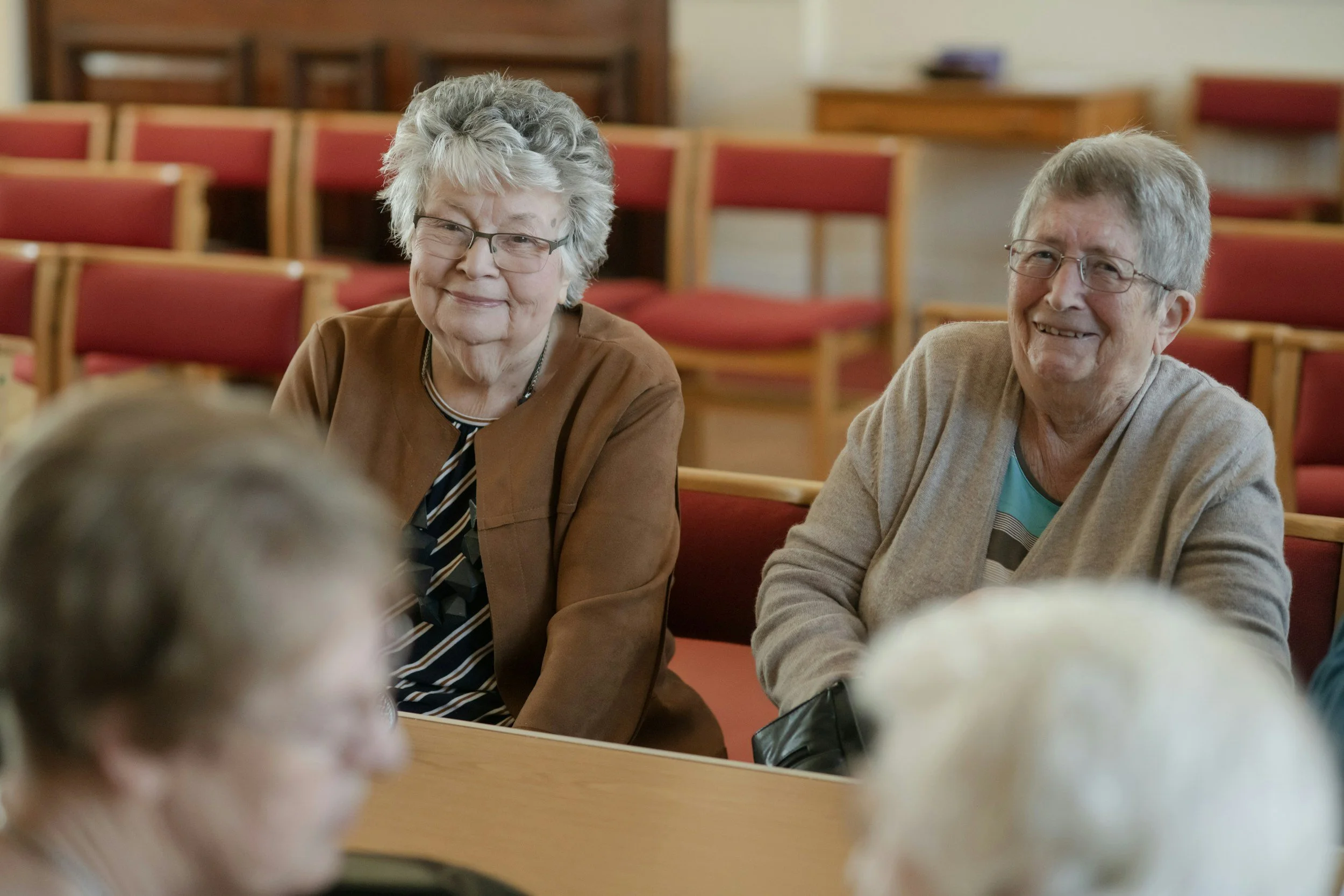 Four older women sit in a group, smiling