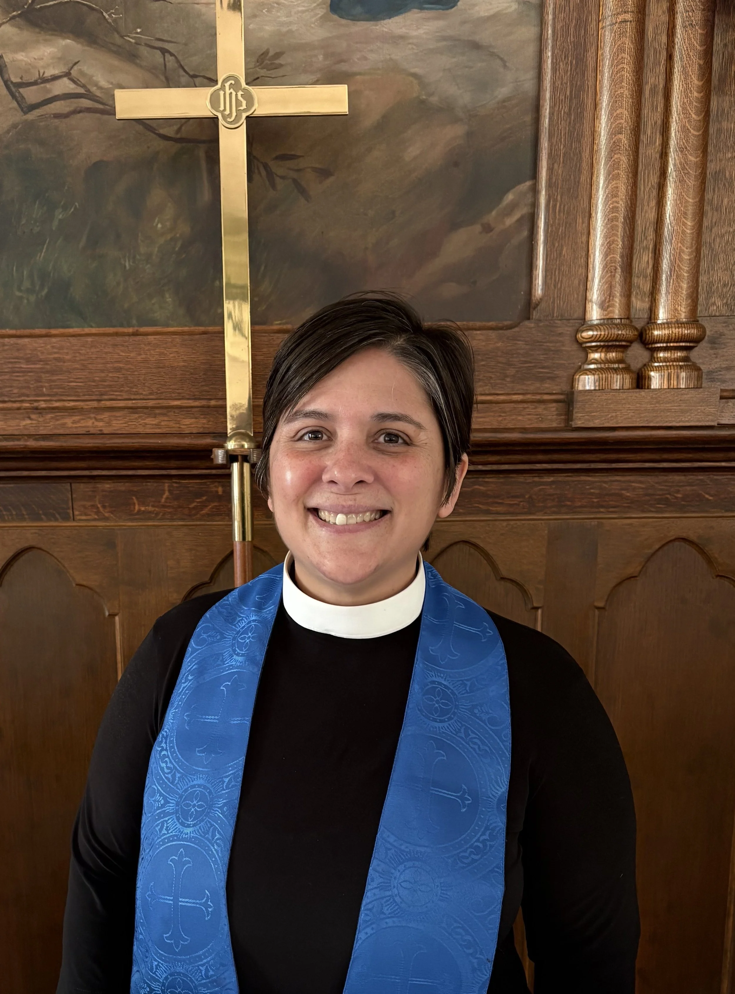 A smiling woman wearing a clerical collar